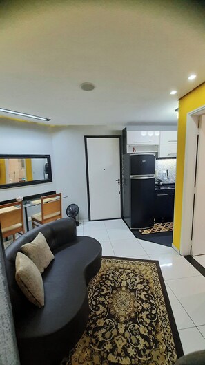 Un espacio habitable compacto con sofá, mesa de comedor y zona de cocina.