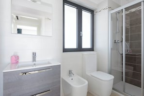 Ein modernes Badezimmer mit Waschbecken, Bidet, Toilette und einer Duschkabine aus Glas.