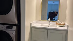 A bathroom with a sink, mirror, and laundry machines.