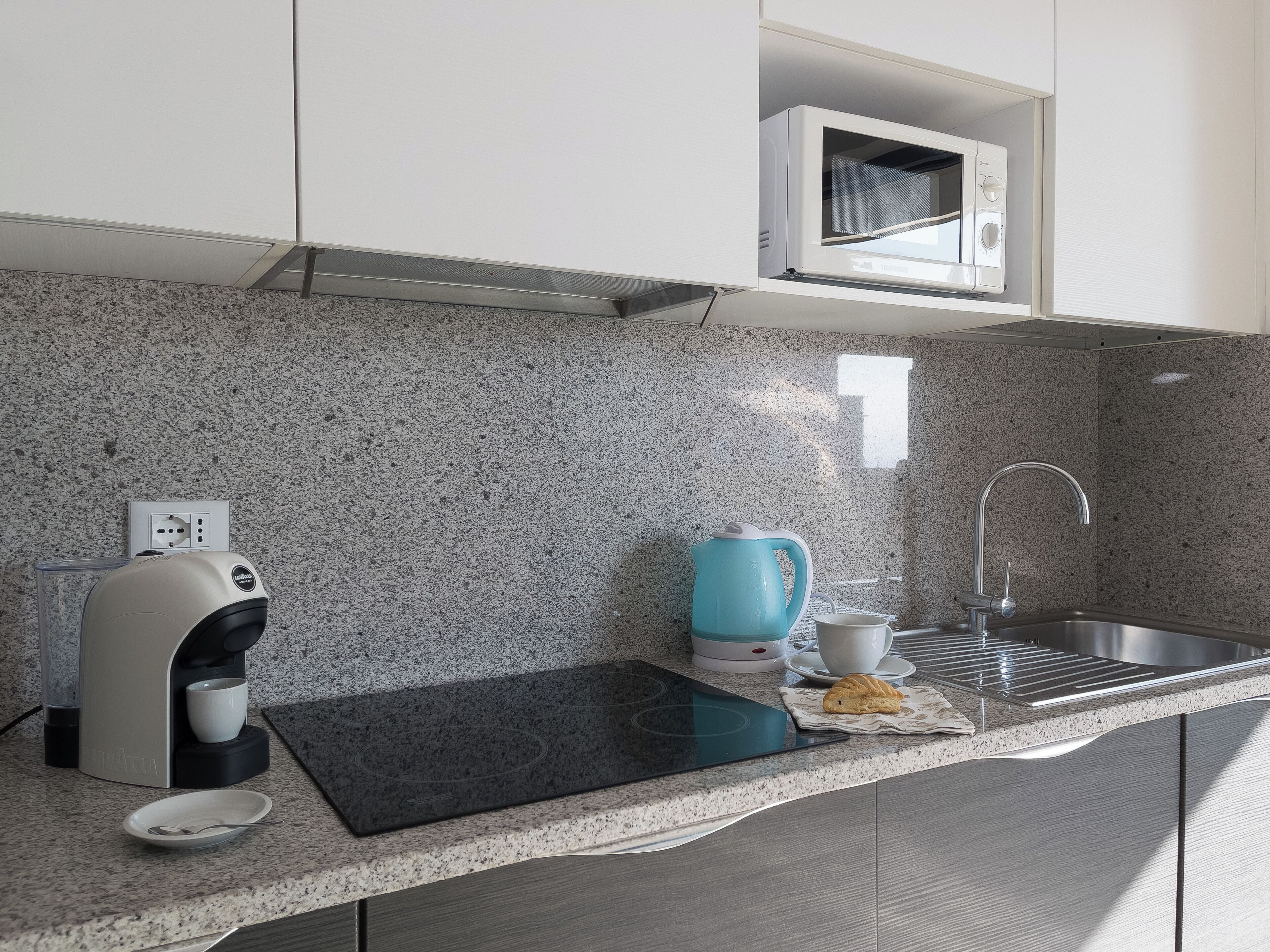A kitchen with a built-in microwave, coffee maker, and sink.