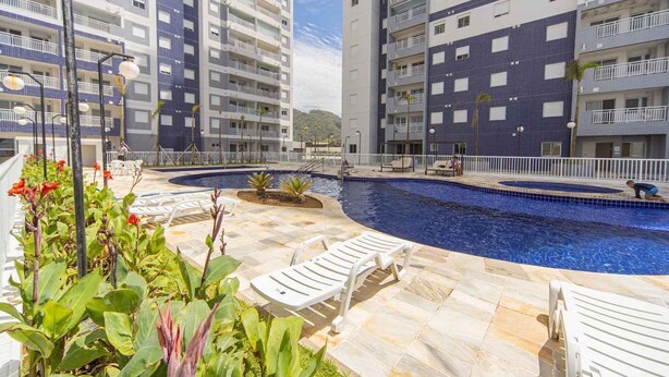 Ein Poolbereich mit Liegestühlen, einer gefliesten Terrasse und Hochhäusern im Hintergrund.