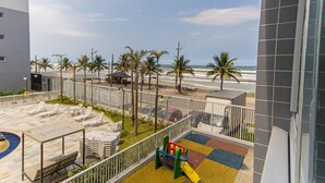 Eine Dachterrasse mit Liegestühlen, einem Spielbereich für Kinder und Blick auf Strand und Meer.