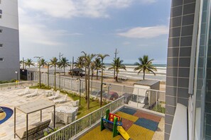 Eine Dachterrasse mit Liegestühlen, einem Spielbereich für Kinder und Blick auf Strand und Meer.