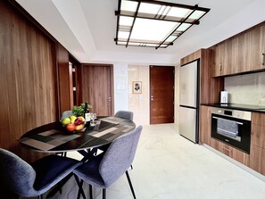 A modern kitchen with a dining area, featuring a built-in oven, a refrigerator, and a skylight. - STAY Finikoudes Nest 1 (Larnaca)