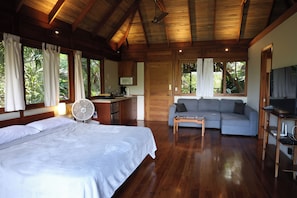 A room with a bed, a sofa, a desk with a computer, and a TV. - Jungle Canopy Bungalow at Taru Rentals (Montezuma)