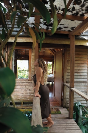 A wooden structure with a covered porch and a view of a building in the background. - Jungle Canopy Bungalow at Taru Rentals (Montezuma)