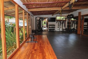 Una palestra con pavimenti in legno, attrezzature per esercizi e un grande specchio.