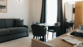 Una sala de estar moderna con sofá, mesa de comedor, sillas y una zona de cocina con fregadero y encimera.