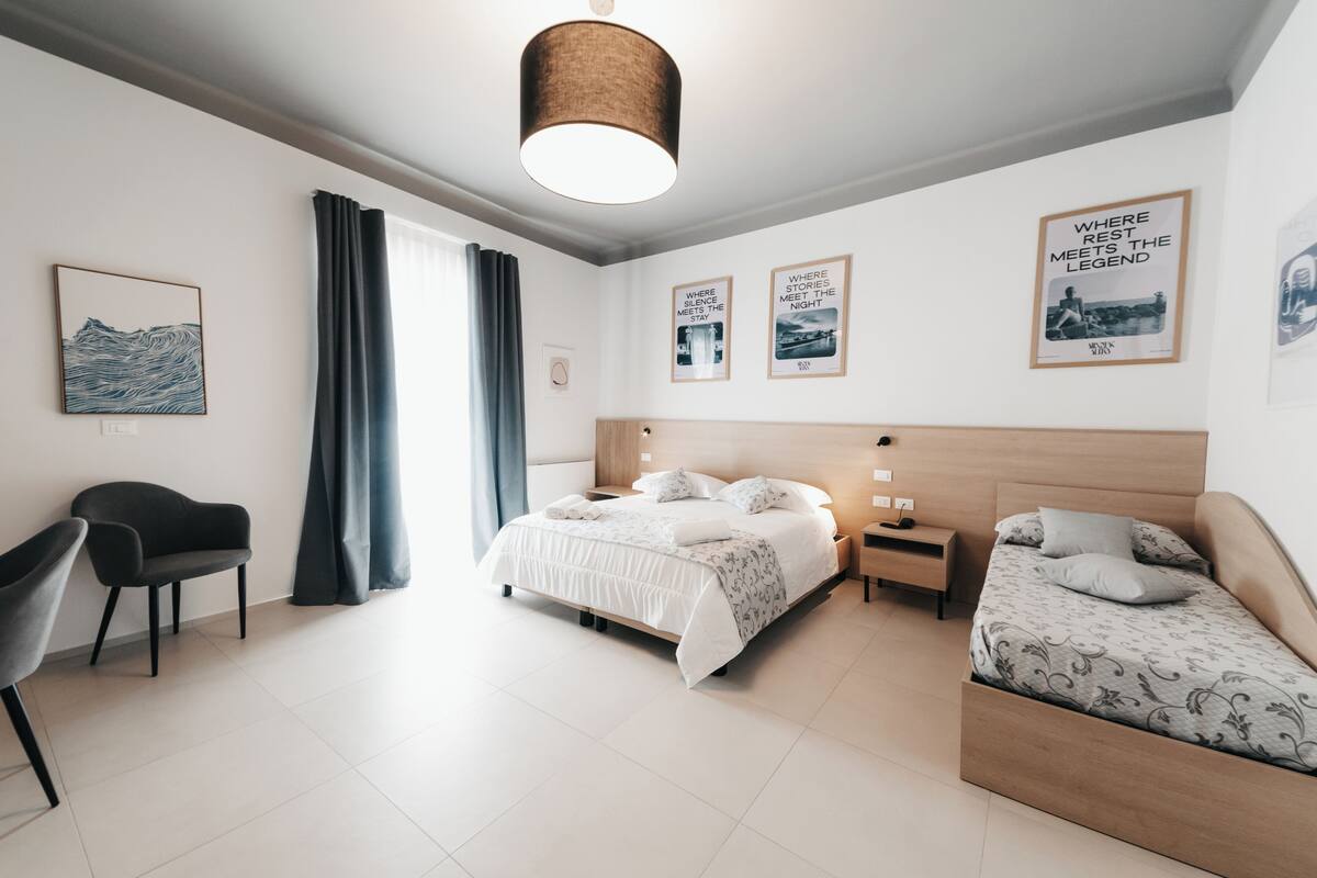 Una habitación de hotel moderna con una cama, mesitas de noche, una silla y obras de arte en las paredes.