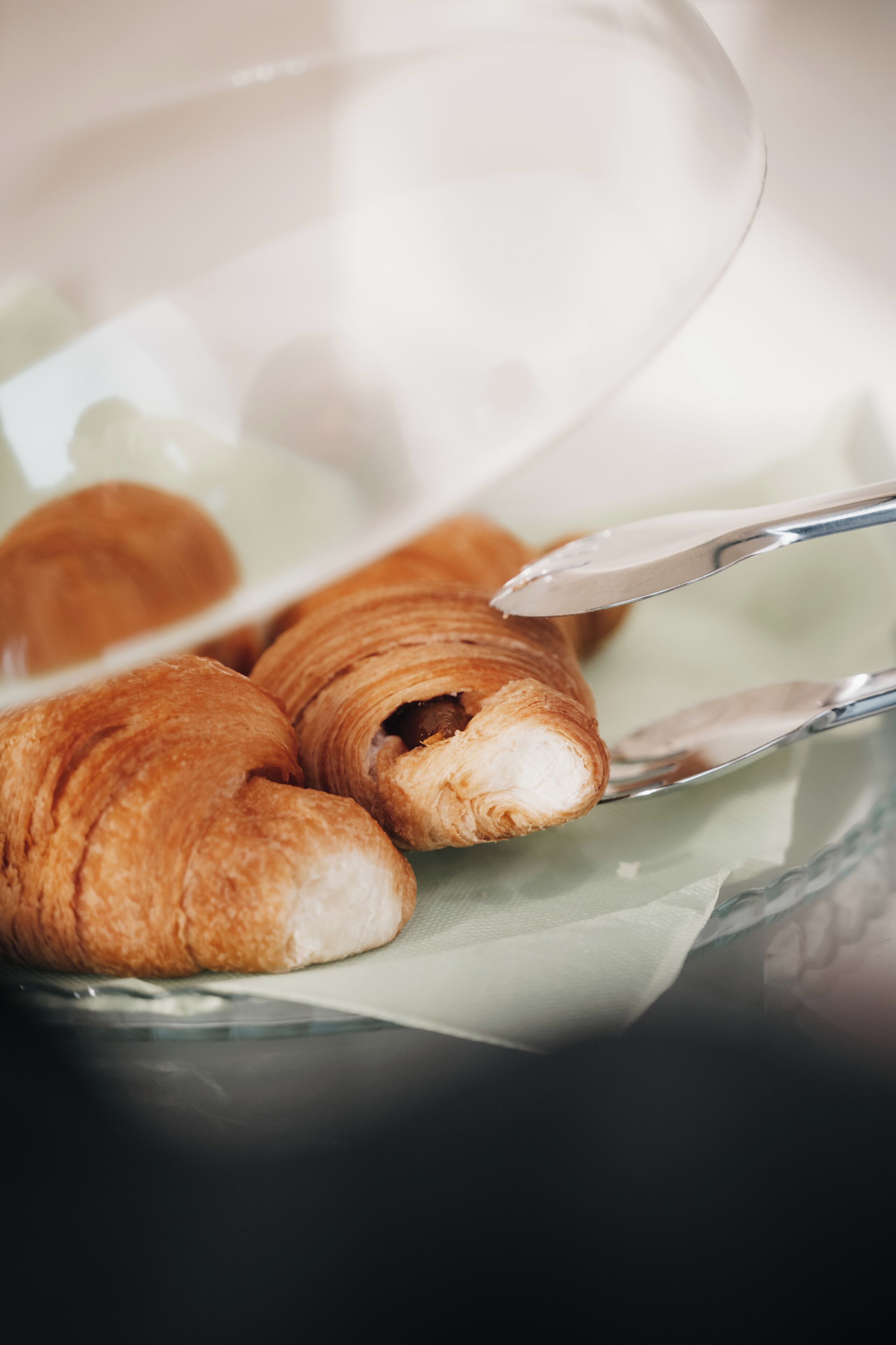 En glasskål med croissanter och en sked.