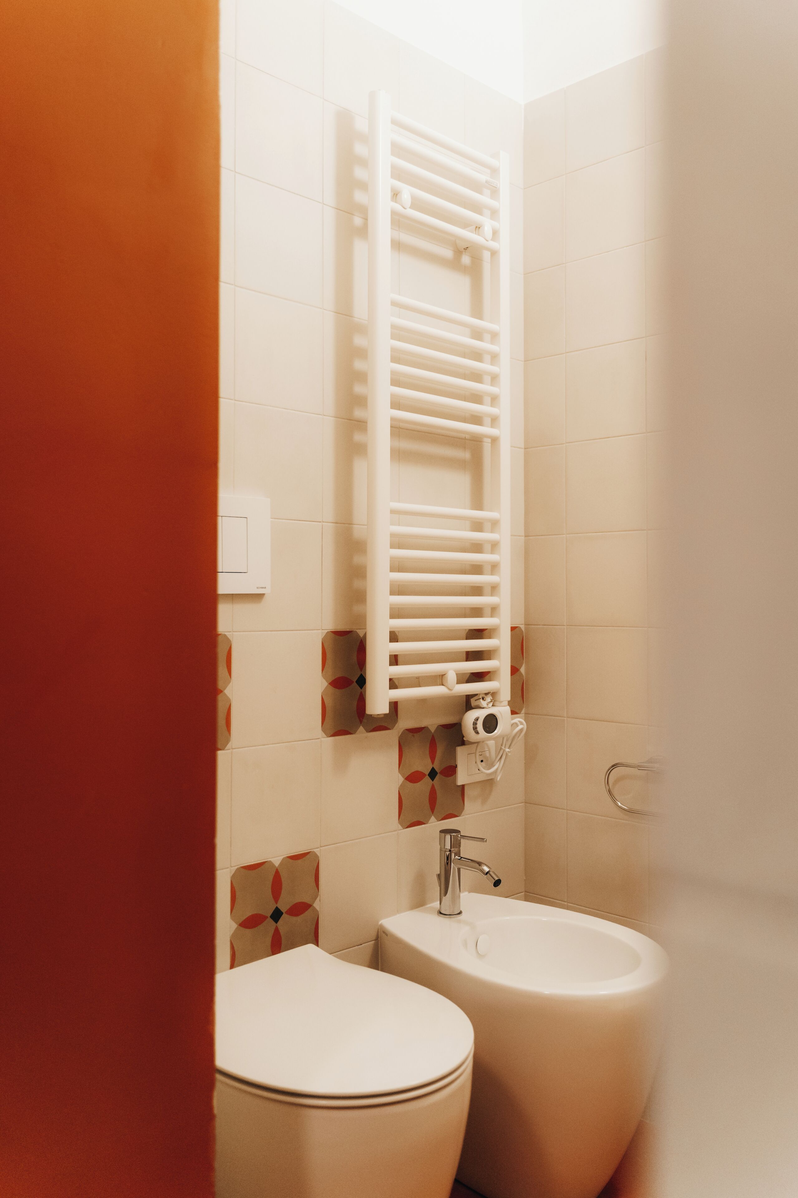 Een badkamer met toilet, bidet en een handdoekhouder.