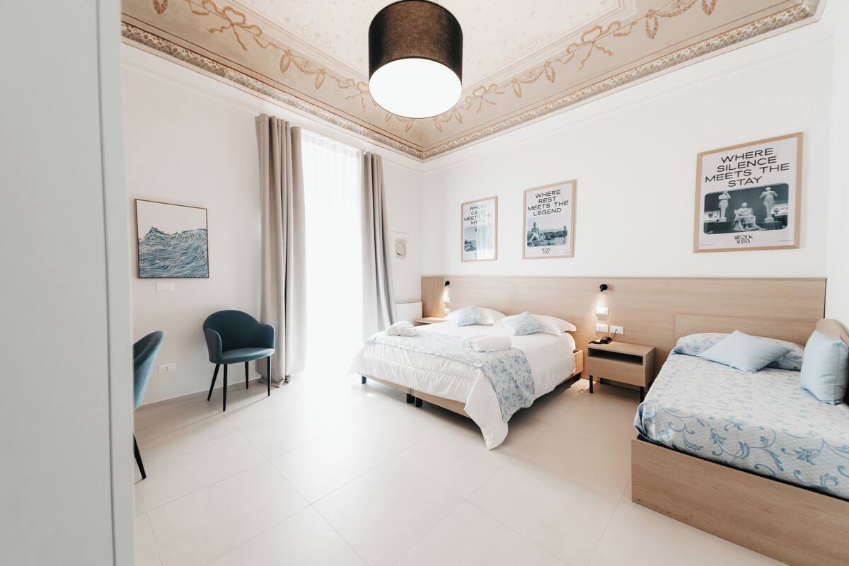 Una habitación de hotel moderna con cama, mesita de noche, lámpara y una silla.