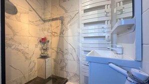 A modern bathroom with a glass shower enclosure, a marble-tiled wall, and a white sink with a mirror. - Seafoam - T1 BIS near the ocean (Mimizan)