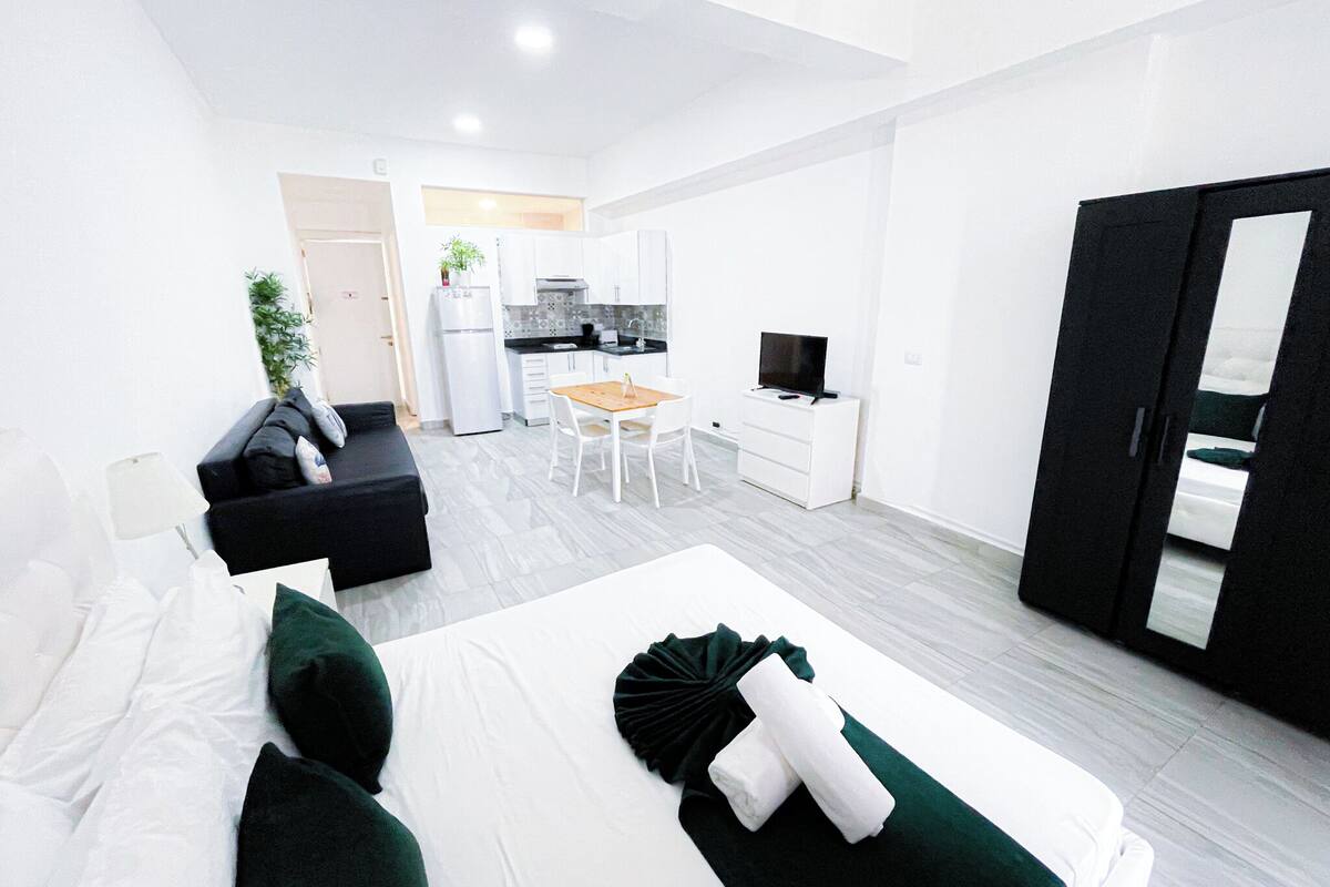 Une chambre d’hôtel compacte comprenant un lit, un canapé, une petite table à manger et, au fond, un coin cuisine.