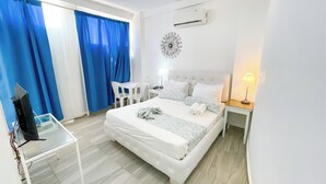 Una camera d'albergo con un letto, una scrivania, una sedia, una TV e un condizionatore d'aria a parete.