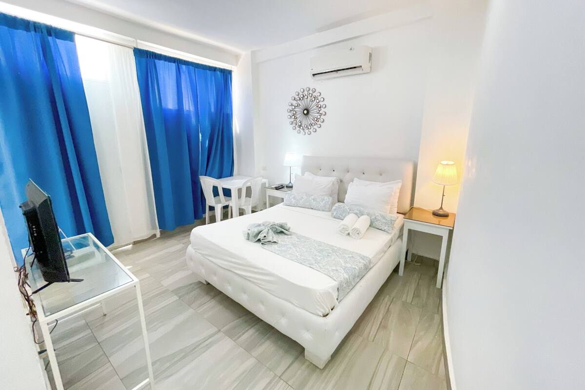 Une chambre d’hôtel équipée d’un lit, d’un bureau, d’une chaise, d’une télévision et d’un climatiseur fixé au mur.