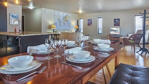 A dining area with a wooden table set for six, white plates, glasses, and cutlery.