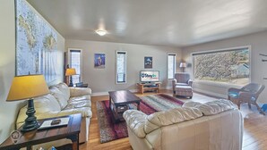 A living room with a sofa, armchair, coffee table, and a television displaying 'StayIn.'