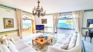 Una sala de estar con sofá, televisión y vista al mar.