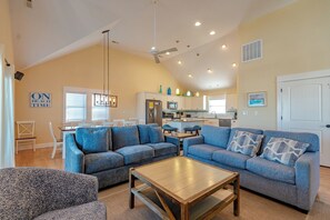 A spacious living room with two sofas, a coffee table, and a dining area with a table and chairs. - JL #087 - Pain Killer - Semi Oceanfront - Heated Private Pool - Hot Tub (Kill Devil Hills)