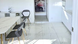 A modern kitchen with a marble floor, a dining table with chairs, and a Buddha statue in the background. - Souplex villa Nice Fabron exclusive pool sea view, 3 min beach, streetcar, shops (Nice)
