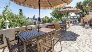 An outdoor patio with wicker furniture, a wooden table, and a thatched umbrella. - Souplex villa Nice Fabron exclusive pool sea view, 3 min beach, streetcar, shops (Nice)