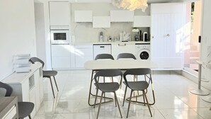 A modern kitchen with white cabinetry, a dining area with a marble table, and a unique light fixture. - Souplex villa Nice Fabron exclusive pool sea view, 3 min beach, streetcar, shops (Nice)