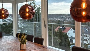 Un comedor moderno con una larga mesa de madera, varias sillas y lámparas colgantes.
