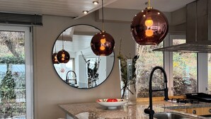 Una cocina moderna con encimera de granito, pileta de acero inoxidable y un espejo redondo.