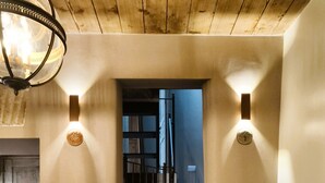 Een trap met houten details, een wandlamp en een deur naar een andere kamer.