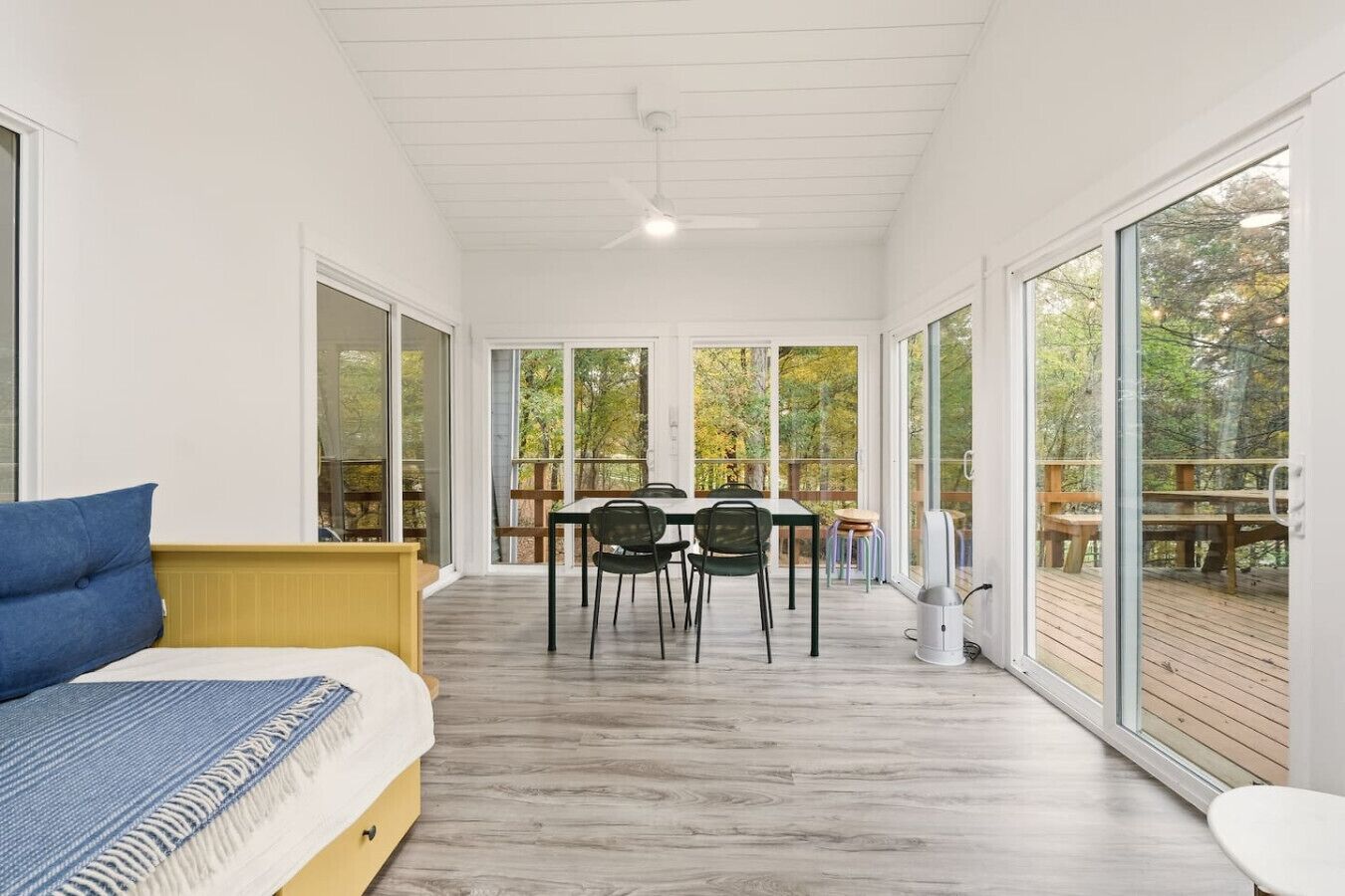 Une chambre moderne équipée d’un lit, d’une table à manger avec des chaises et de grandes fenêtres donnant sur l’extérieur.