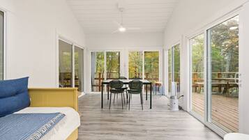 Une chambre moderne équipée d’un lit, d’une table à manger avec des chaises et de grandes fenêtres donnant sur l’extérieur.