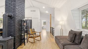 Un intérieur moderne avec une cheminée, un fauteuil à bascule en bois, un canapé et une vue par la fenêtre.