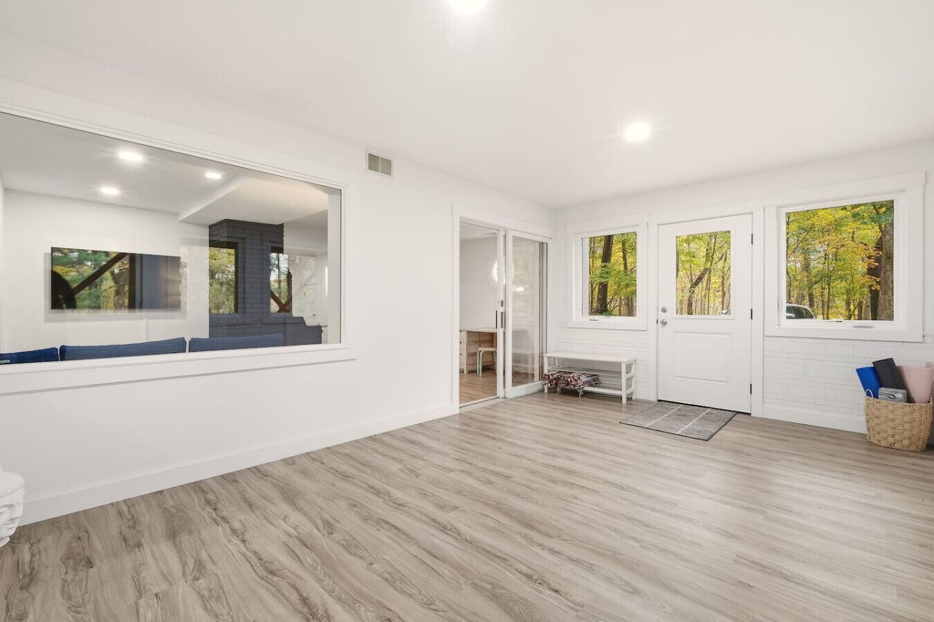 A spacious room with a large mirror, a bench, and a door leading to another area.