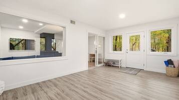 A spacious room with a large mirror, a bench, and a door leading to another area.