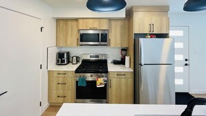 Una cocina moderna con armarios de madera, electrodomésticos de acero inoxidable e iluminación colgante.