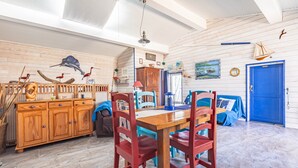 Zona pranzo con tavolo e sedie in legno, una porta blu e un armadietto in legno.