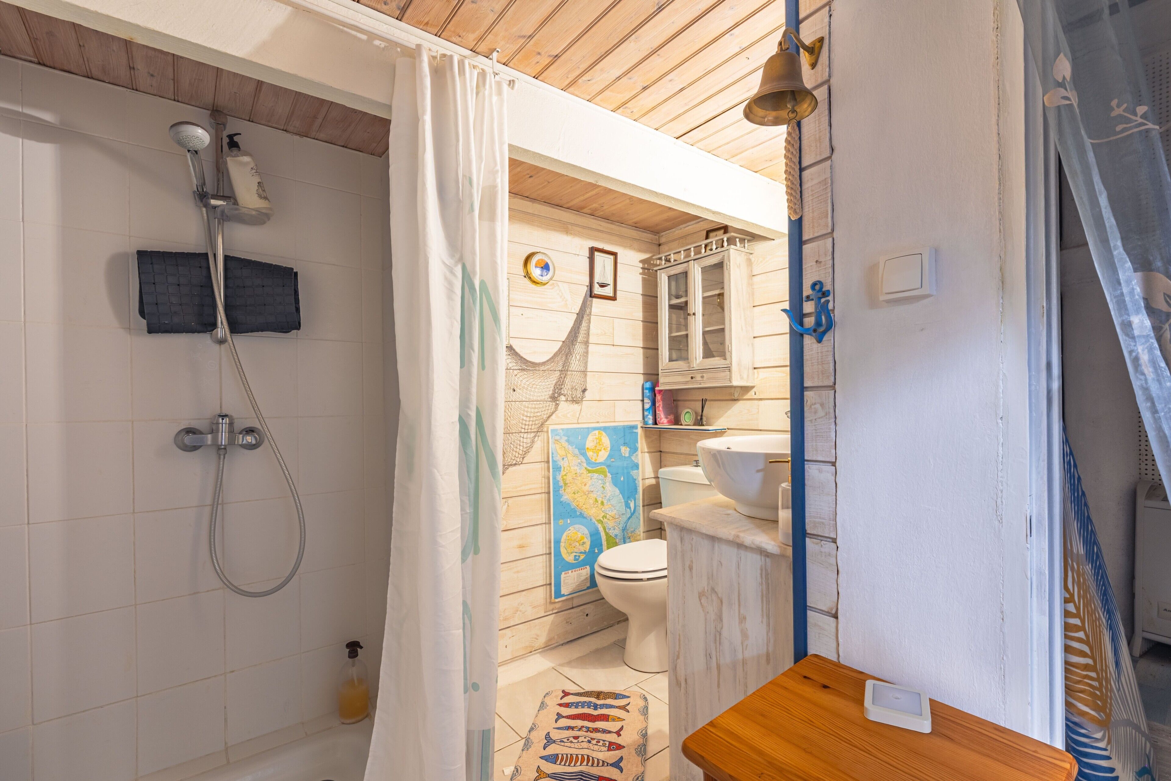 A bathroom with a shower, toilet, sink, and wooden bench.