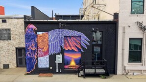 Un bâtiment à la façade noire, orné d’une fresque représentant un aigle, et doté d’un petit espace extérieur aménagé en coin salon.