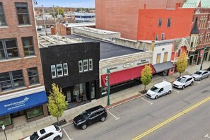 A street view with a black building with large windows, a red awning, and a sign for 'Herald's Home Entertainment'. - Main Street Room & Board (Mount Vernon)