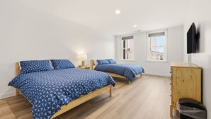 A room with two beds, a wooden cabinet, a TV, and a window.