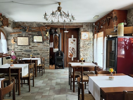 A rustic interior with stone walls, wooden furniture, a chandelier, and a vintage refrigerator.