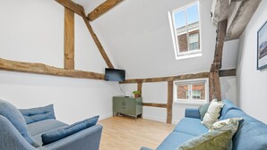 Een kamer met zichtbare houten balken, een groene kast en een blauwe bank.