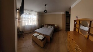 A bedroom with a bed, bedside tables, a dresser, a mirror, a window with curtains, and a ceiling fan. - Giovi's House (Moquegua)