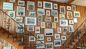 A staircase with wooden walls adorned with framed landscape paintings.