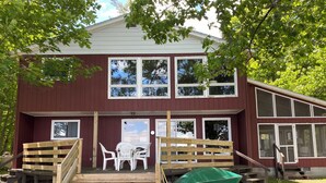 A two-story building with a wooden deck, a green boat, and a white paddle boat.