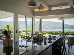 Eine moderne Küche mit einer großen Kochinsel, großen Fenstern und Blick auf einen See und Berge.