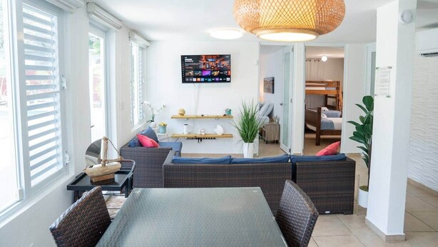 Una sala de estar moderna con comedor, una lámpara de fibra natural grande y un televisor de pantalla plana montado en la pared.