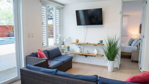 Una sala de estar con muebles de mimbre, un televisor de pantalla plana y una planta en maceta.
