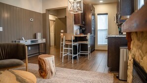 A modern kitchen with wooden cabinets, a dining area with a wooden table and chairs, and a visible stove. - Superior Queen Two-Bedroom Cottage (Bronson)